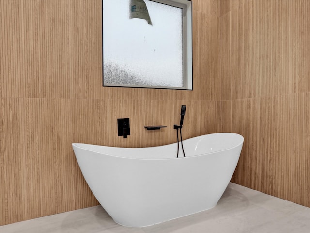 bathroom with a bathing tub and wood walls