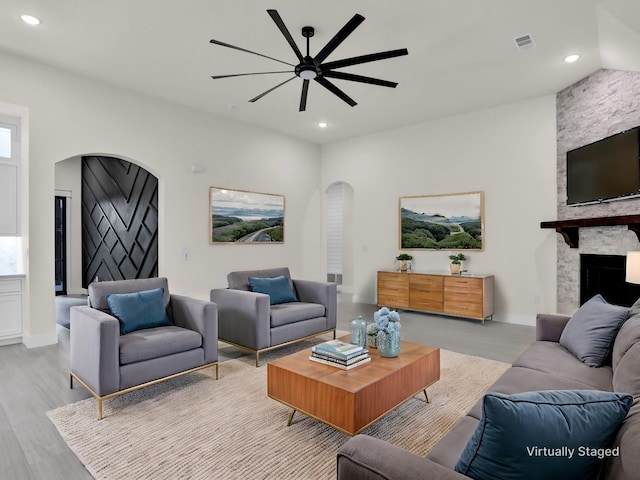 living room with ceiling fan, a fireplace, and light hardwood / wood-style flooring