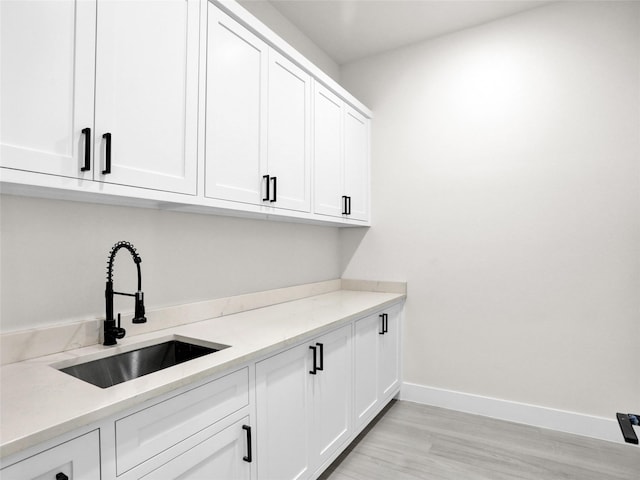 laundry room featuring light wood-type flooring and sink