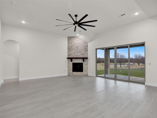 unfurnished living room featuring ceiling fan, a fireplace, high vaulted ceiling, and light wood-type flooring