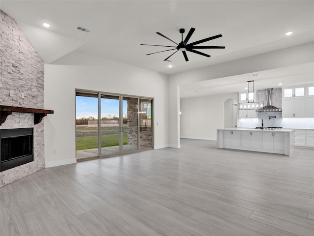 unfurnished living room featuring a fireplace, ceiling fan, and light hardwood / wood-style flooring