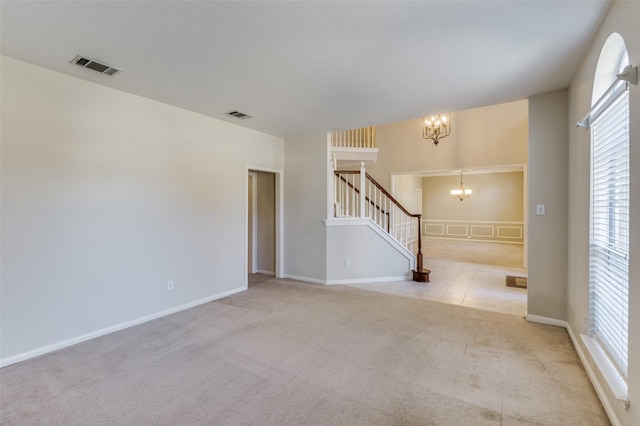 unfurnished room with light colored carpet and a notable chandelier