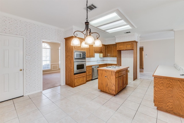 kitchen featuring appliances with stainless steel finishes, hanging light fixtures, a center island, light tile patterned floors, and crown molding