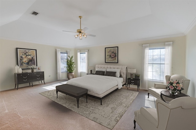 carpeted bedroom with a raised ceiling, crown molding, and ceiling fan