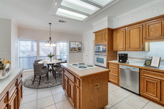 kitchen with crown molding, a chandelier, hanging light fixtures, a kitchen island, and stainless steel appliances