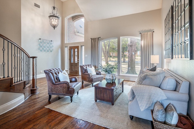 living room featuring hardwood / wood-style floors, a towering ceiling, and an inviting chandelier