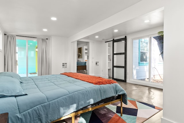 bedroom featuring concrete flooring, a barn door, and access to outside