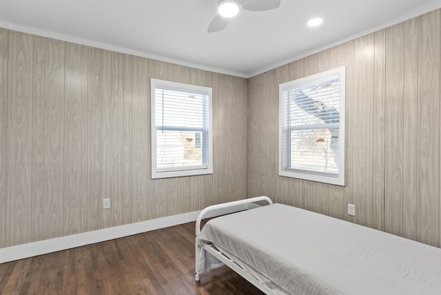 bedroom featuring wood walls, ceiling fan, and dark hardwood / wood-style floors