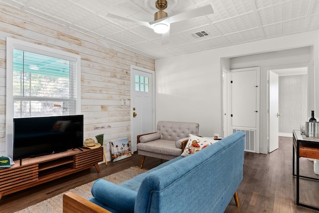 living room featuring ceiling fan, dark hardwood / wood-style floors, plenty of natural light, and wood walls