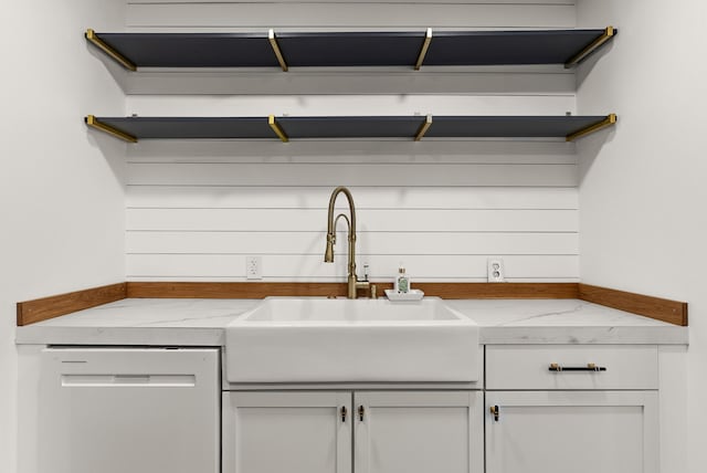 kitchen with white cabinetry, light stone countertops, sink, and white dishwasher