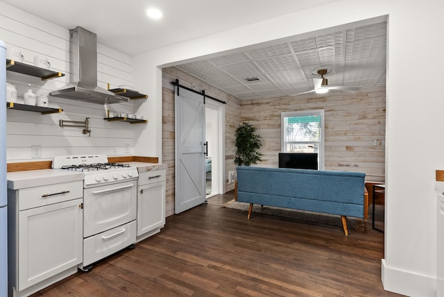 kitchen featuring a barn door, wooden walls, white gas stove, and island exhaust hood