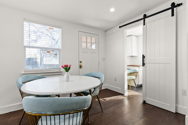 dining area with dark hardwood / wood-style flooring and a barn door