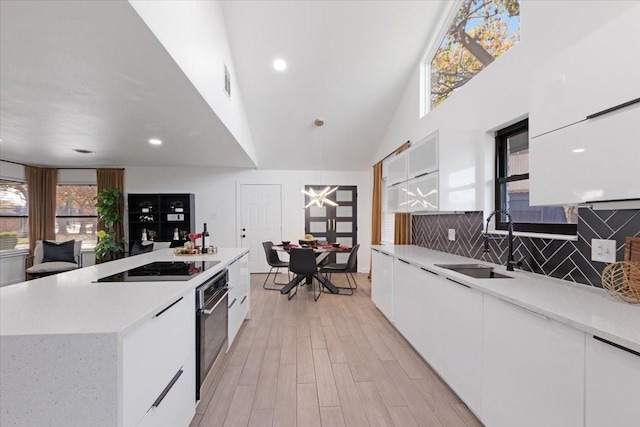 kitchen featuring white cabinetry, sink, oven, a kitchen island, and light wood-type flooring