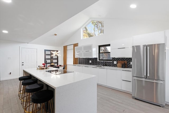 kitchen featuring a center island, stainless steel fridge, light wood-type flooring, and white cabinetry