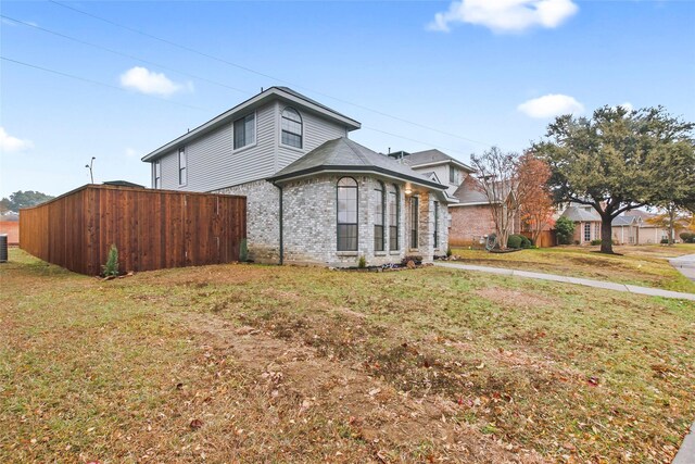 view of side of home with central AC and a yard