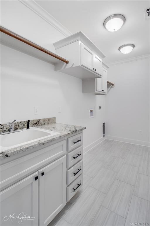 laundry room with hookup for an electric dryer, hookup for a washing machine, cabinets, ornamental molding, and sink