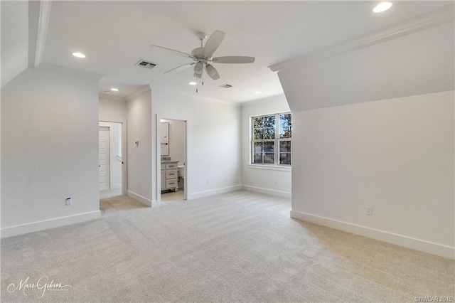 interior space featuring lofted ceiling, ensuite bathroom, ceiling fan, ornamental molding, and light colored carpet