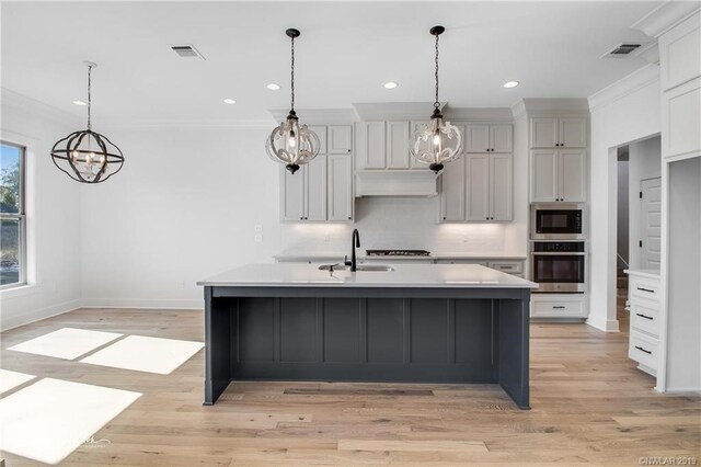 kitchen with pendant lighting, a large island, sink, and appliances with stainless steel finishes