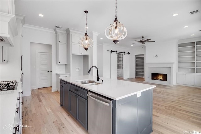 kitchen with sink, a barn door, an island with sink, white cabinets, and appliances with stainless steel finishes