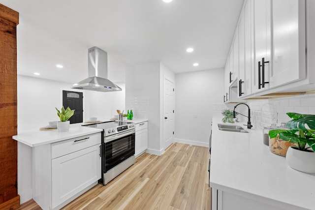 kitchen with white cabinetry, sink, light hardwood / wood-style flooring, stainless steel electric stove, and exhaust hood