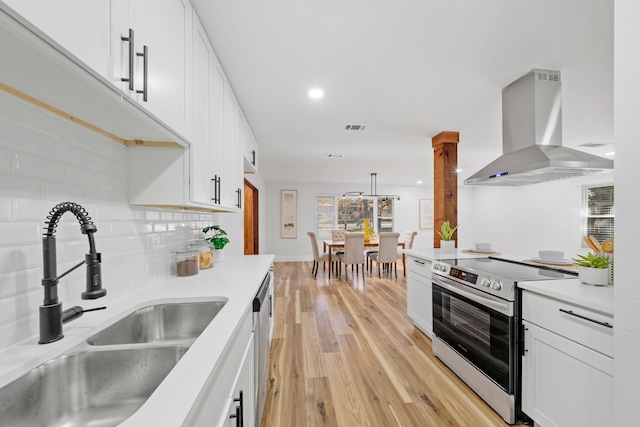 kitchen with white cabinetry, sink, wall chimney exhaust hood, stainless steel appliances, and light hardwood / wood-style flooring