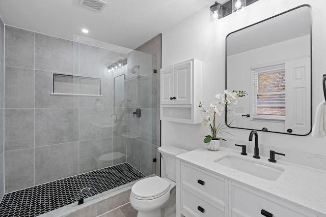 bathroom with tile patterned floors, vanity, toilet, and walk in shower