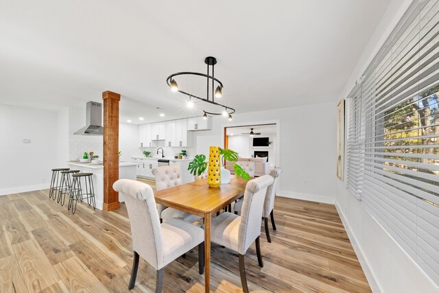 dining area featuring a notable chandelier, sink, and light hardwood / wood-style flooring