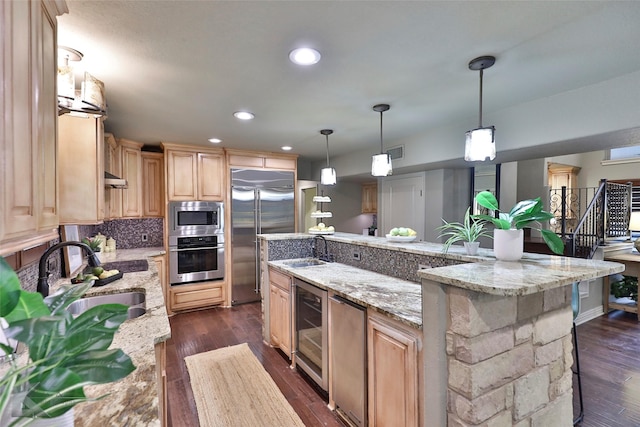 kitchen featuring a center island, sink, dark wood-type flooring, built in appliances, and a breakfast bar area