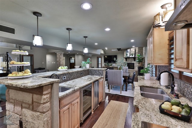 kitchen featuring pendant lighting, sink, dark hardwood / wood-style flooring, beverage cooler, and decorative columns