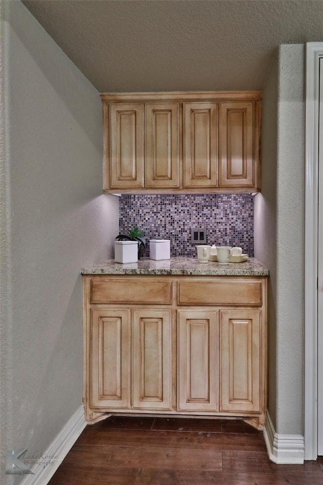 bar featuring decorative backsplash, light brown cabinetry, and dark wood-type flooring