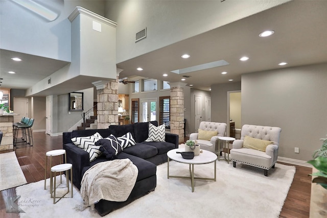 living room with wood-type flooring, ornate columns, and a towering ceiling