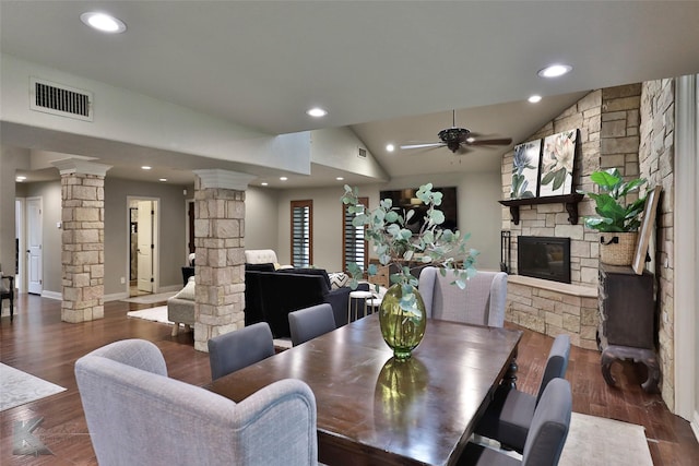 dining area with ornate columns, ceiling fan, dark hardwood / wood-style flooring, vaulted ceiling, and a fireplace