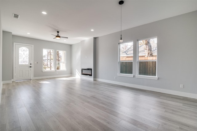 unfurnished living room with ceiling fan, a healthy amount of sunlight, and light wood-type flooring