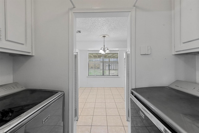 kitchen with white cabinets, washer / dryer, a textured ceiling, and an inviting chandelier