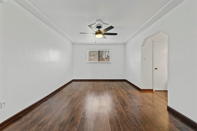 empty room with a textured ceiling, dark hardwood / wood-style floors, and ceiling fan