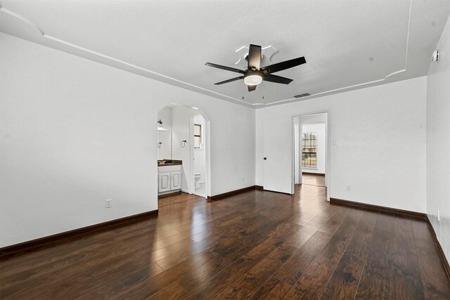 empty room with ceiling fan and dark wood-type flooring