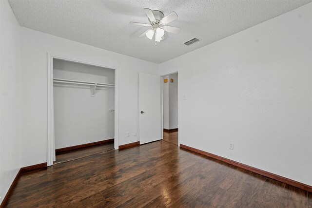 unfurnished bedroom featuring ceiling fan, dark hardwood / wood-style floors, a textured ceiling, and a closet