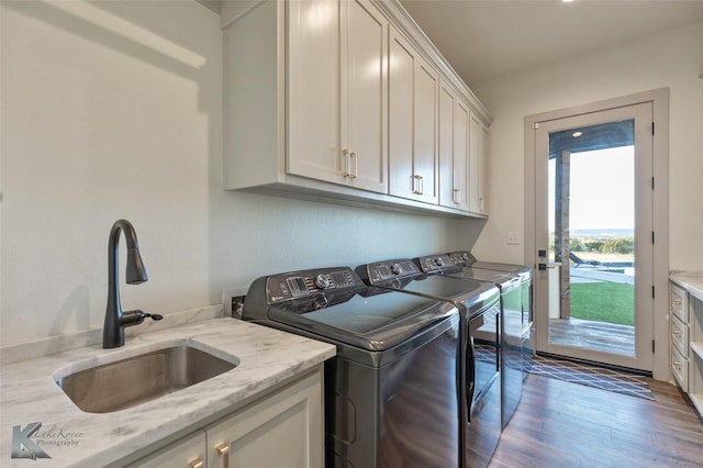 laundry room featuring dark hardwood / wood-style floors, washer and dryer, cabinets, and sink