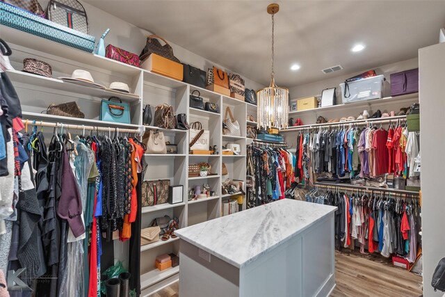 walk in closet featuring a notable chandelier and light wood-type flooring