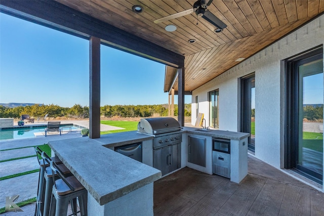 view of patio / terrace featuring exterior kitchen, area for grilling, a wet bar, and ceiling fan