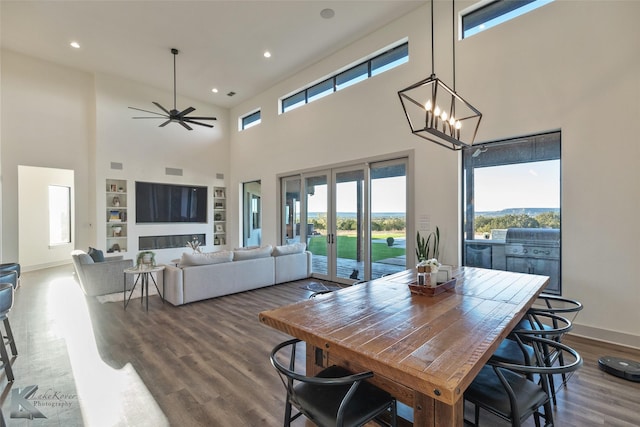 dining space featuring ceiling fan with notable chandelier, hardwood / wood-style floors, a towering ceiling, and french doors