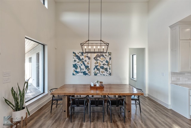 dining area featuring plenty of natural light, wood-type flooring, and a high ceiling