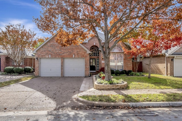 view of front of property featuring a garage, brick siding, driveway, and a front lawn