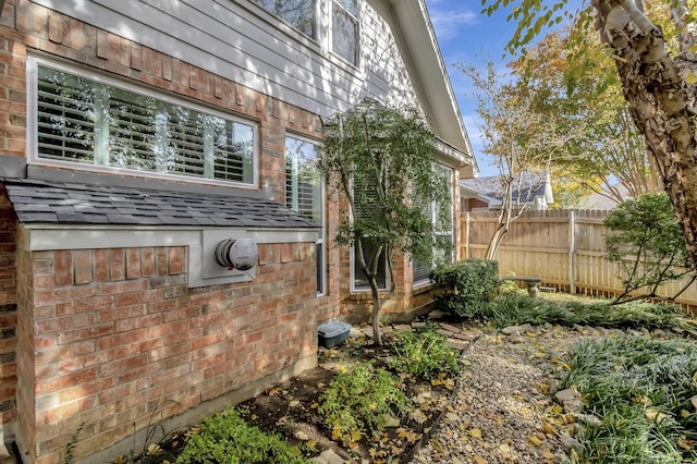 view of property exterior featuring fence and brick siding