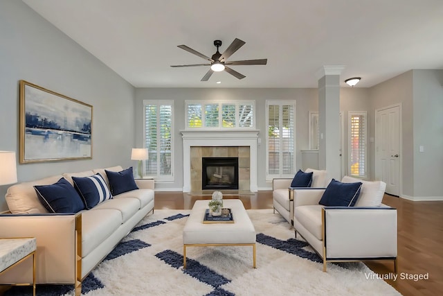 living room featuring a healthy amount of sunlight, a tiled fireplace, baseboards, and wood finished floors