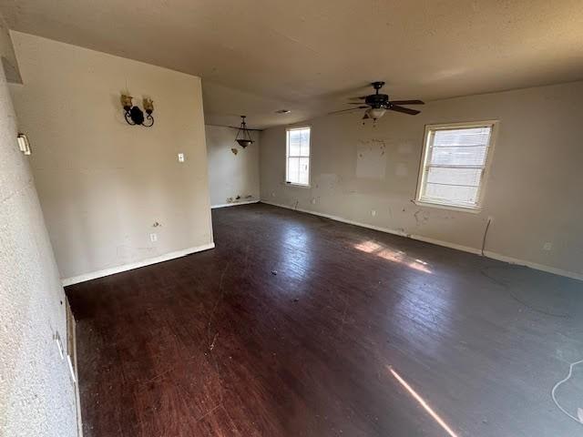 spare room with ceiling fan, dark wood-type flooring, and a wealth of natural light