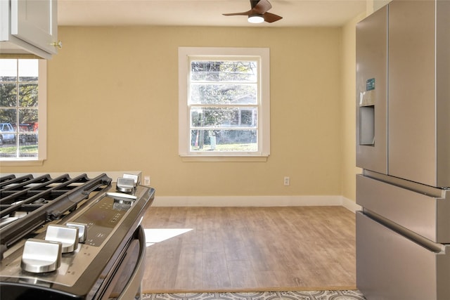 kitchen with stainless steel stove, white cabinetry, sink, kitchen peninsula, and wall chimney exhaust hood