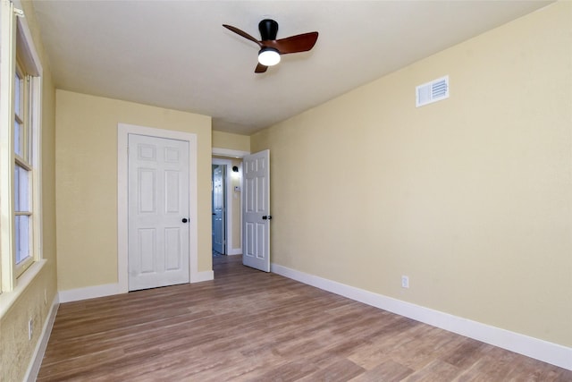 unfurnished bedroom featuring hardwood / wood-style floors, a closet, and ceiling fan