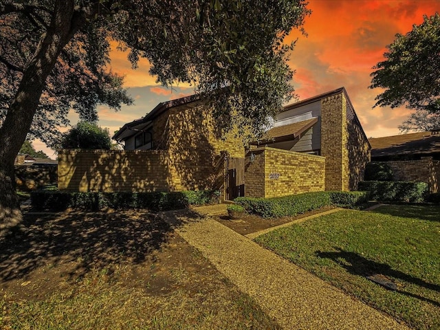 property exterior at dusk with a lawn