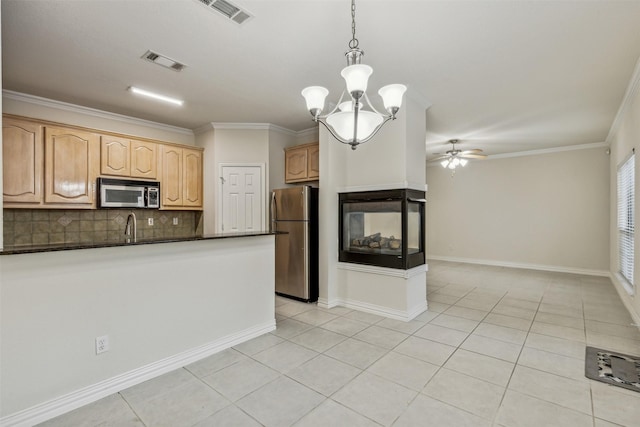 kitchen with decorative backsplash, appliances with stainless steel finishes, ceiling fan with notable chandelier, light tile patterned floors, and decorative light fixtures